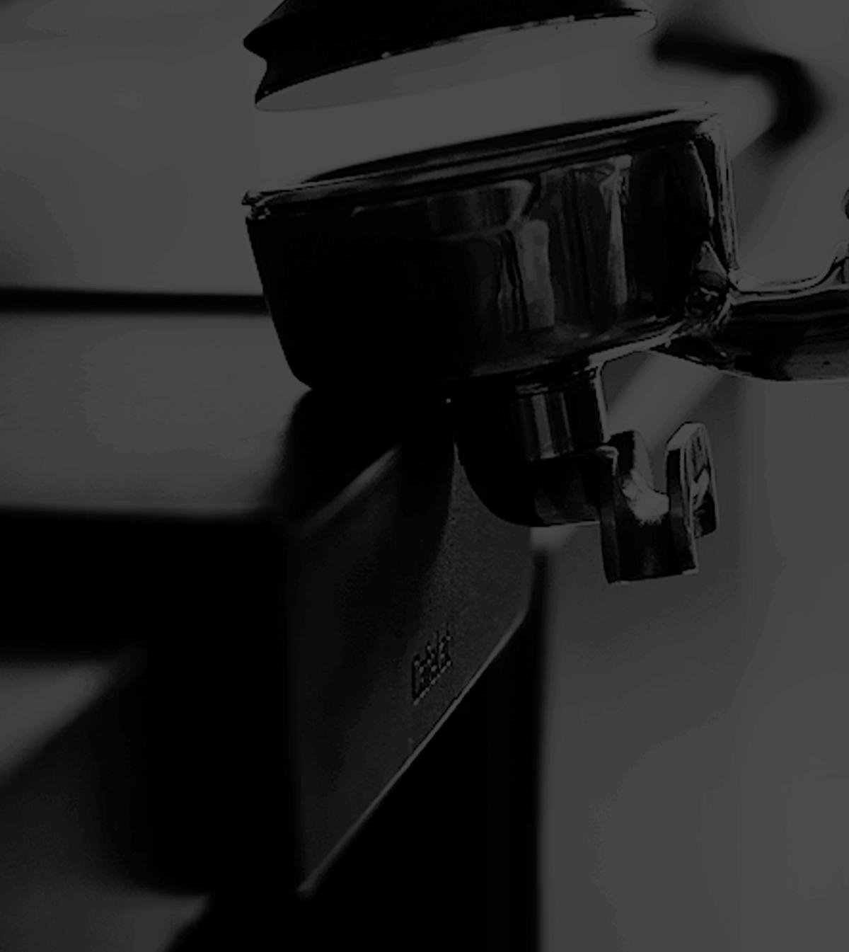 Black and white close-up of a hand pressing a tamper into a portafilter